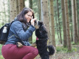 Eine Frau übt mit ihrem Hund im Wald